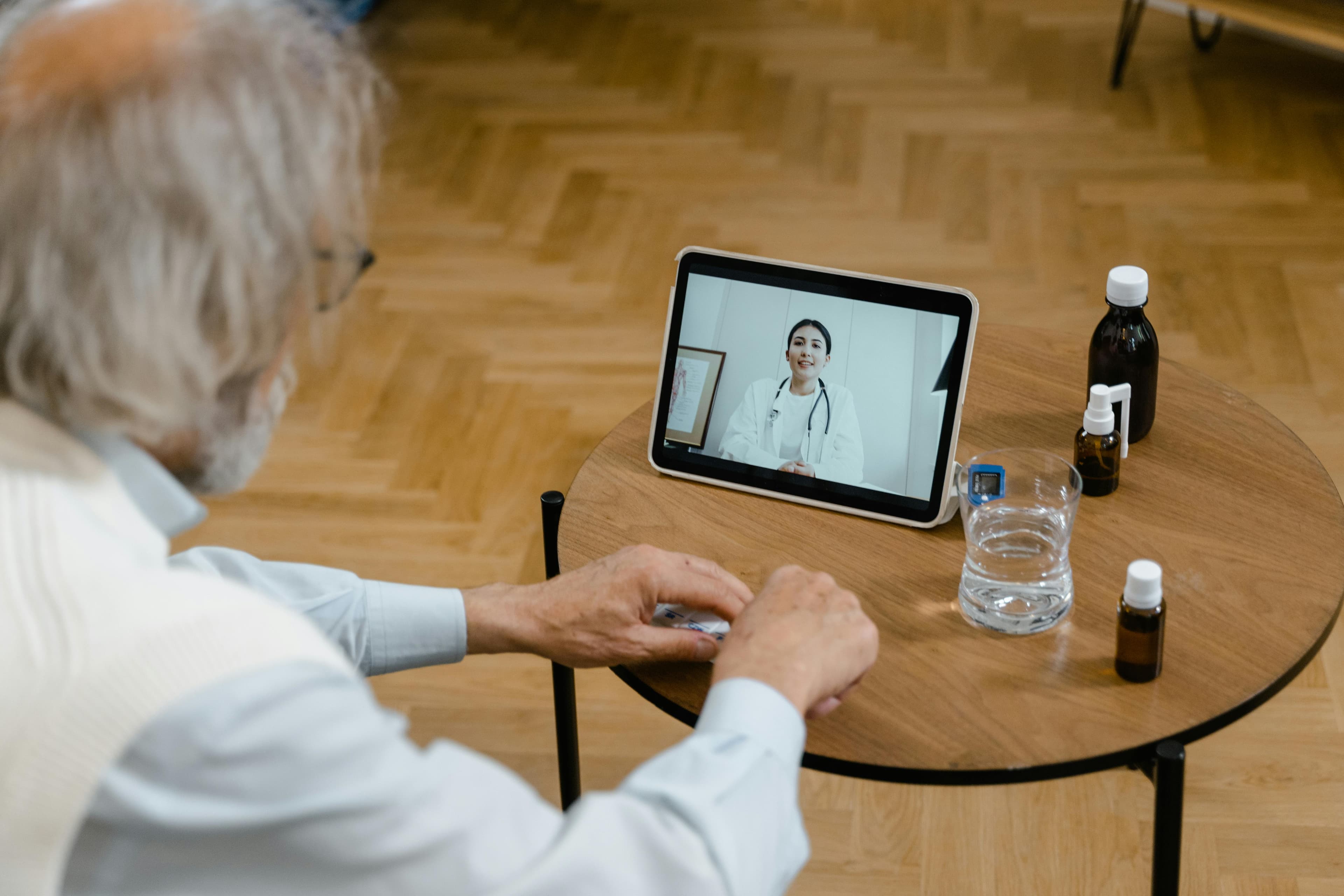 An elderly man participates in a telemedicine session using a tablet