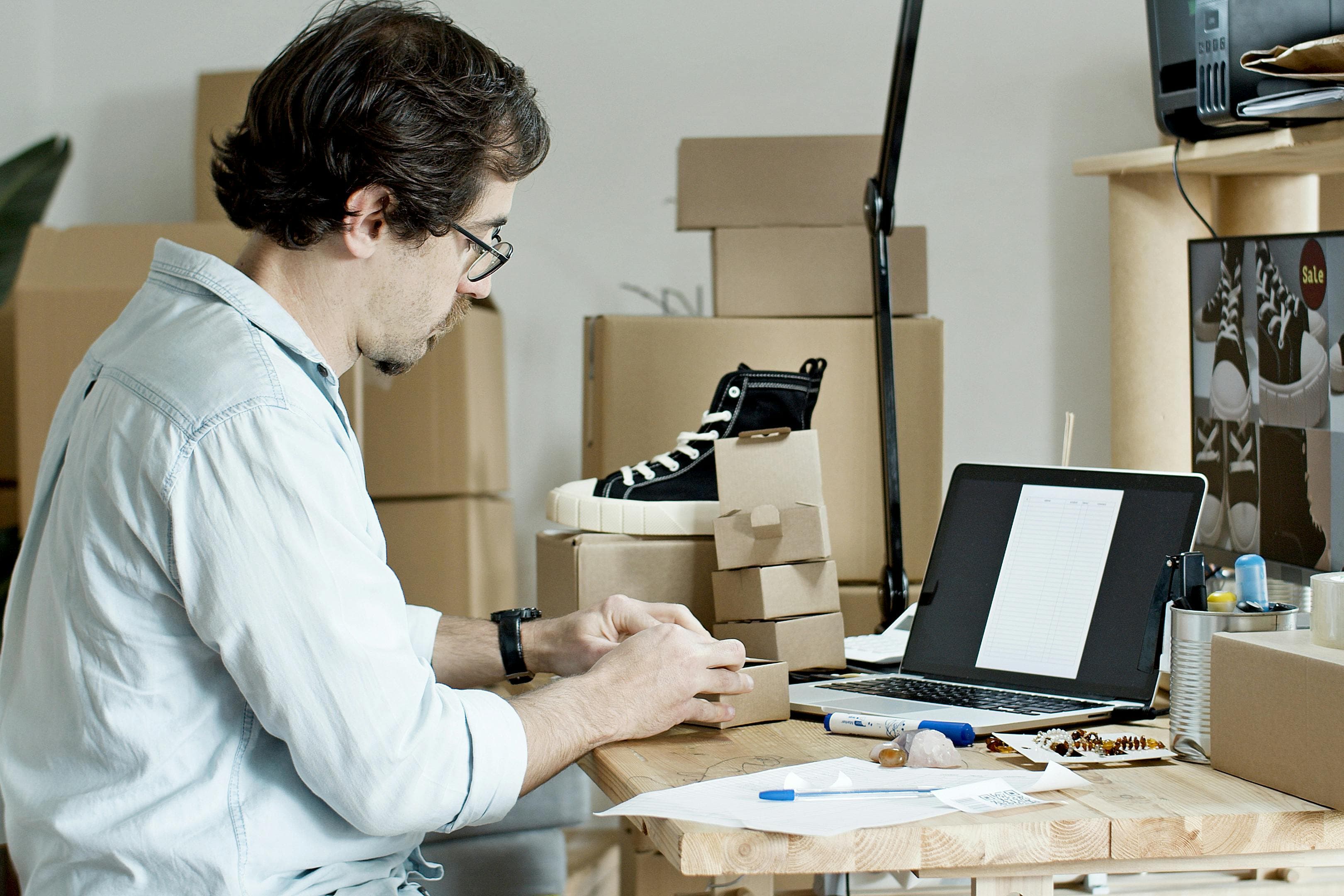 Businessman packing products and managing an online store from his desk with a laptop