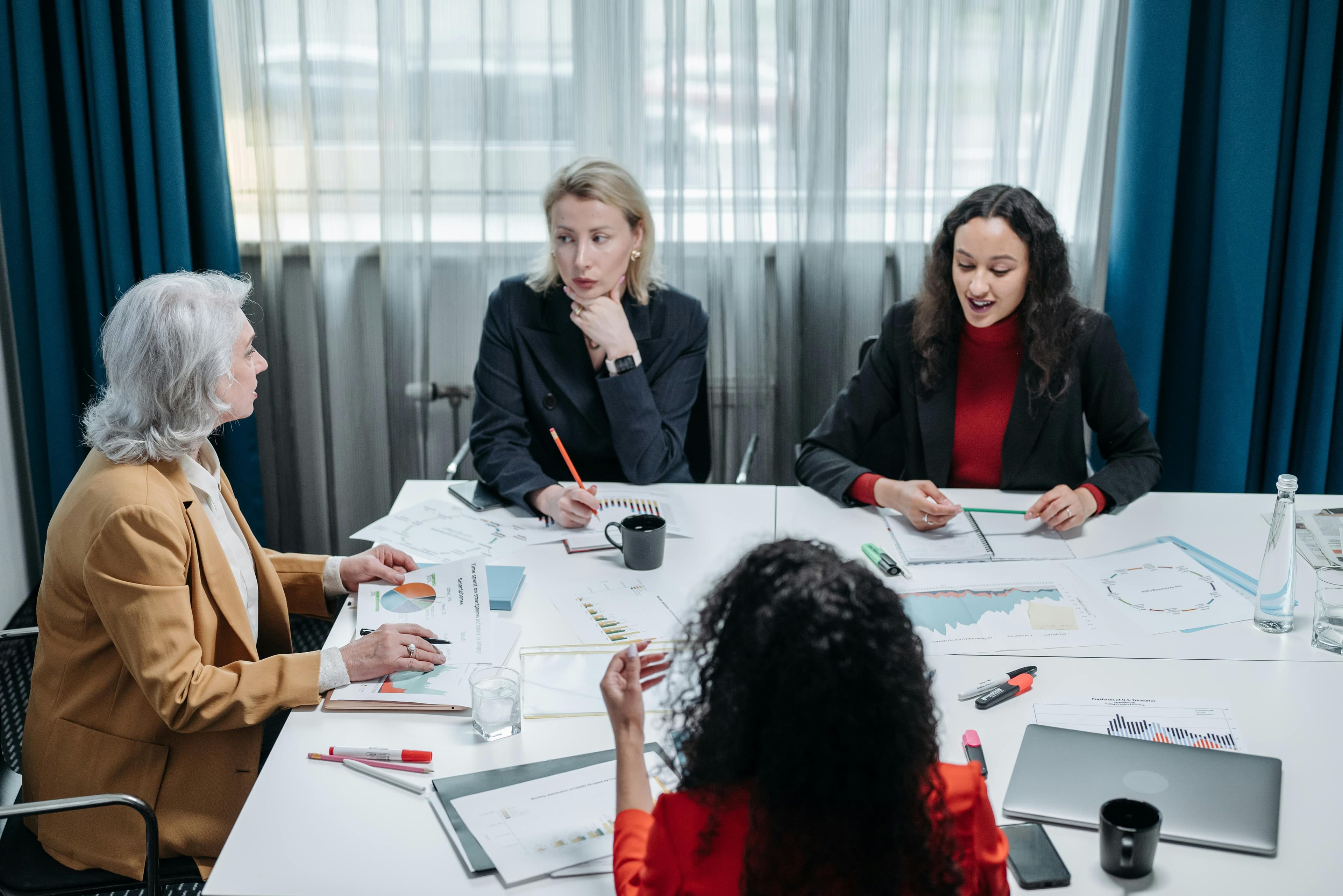 Four professional women engaged in a productive office meeting, discussing business plans
